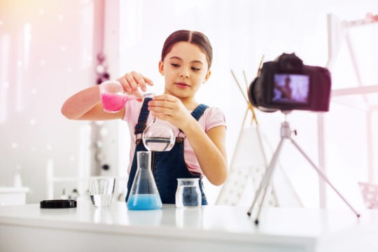 Young girl conducting a science experiment at home on video.