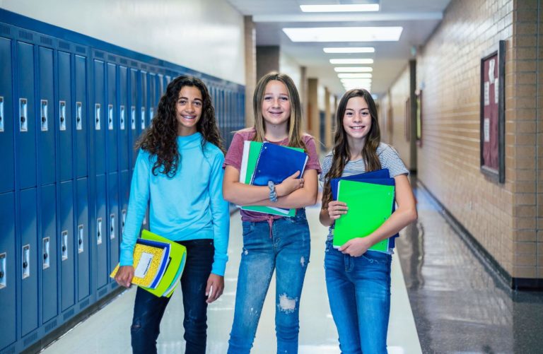 Three middle school girls standing in a school hallway